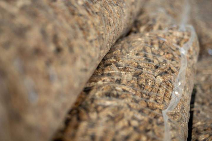 Gros plan sur des granulés de bois de haute qualité, brillants et uniformes, empilés dans un sac transparent avec un label de certification visible, lumière naturelle, photo réaliste.